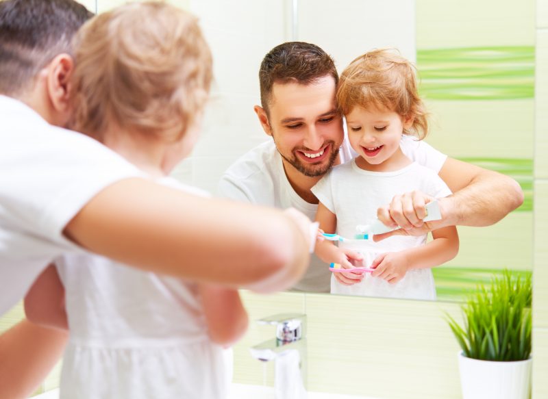 Dad Helping Kid Brush Teeth